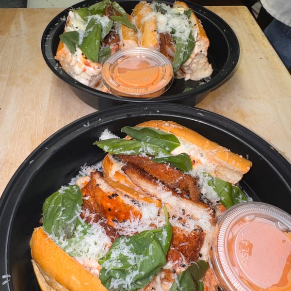 Two black bowls of Napoli's Italian sandwiches with fried chicken, basil, cheese, and sauce.