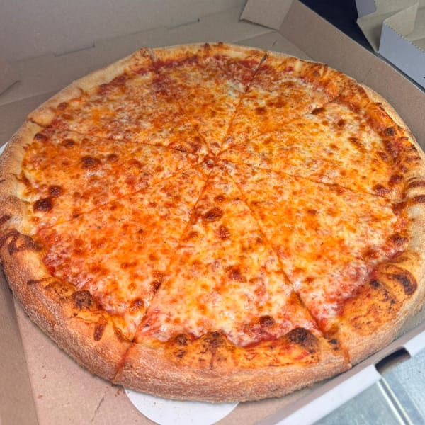 A whole Napoli Pizza and Italian Cuisine cheese pizza, cut into slices, in a cardboard box.